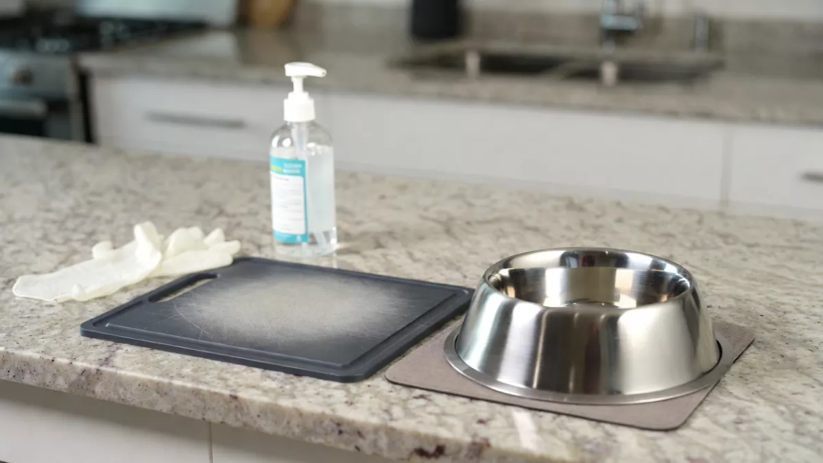 Clean kitchen counter with separate equipment and gloves for preparing raw meat for cats.